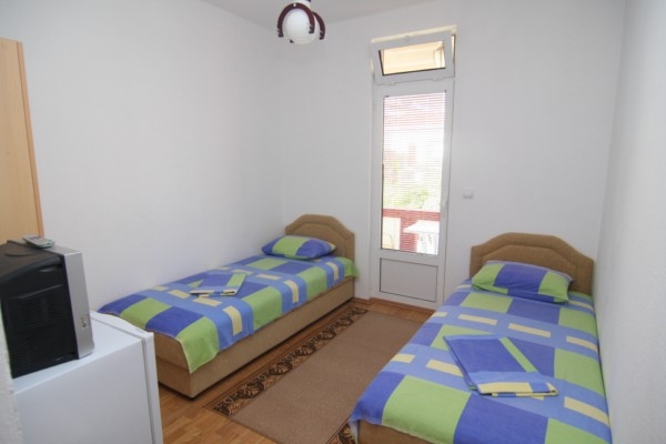 Sypialnia z dwoma pojedynczymi łóżkami w hotelu w mieście Bar, Czarnogóra, z wyjściem na balkon i jasnym wykończeniem.