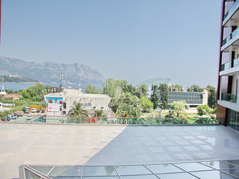 Blick von der Terrasse eines Bürogebäudes in Budva, Montenegro: Panorama auf das Meer, die Berge und die städtische Infrastruktur.