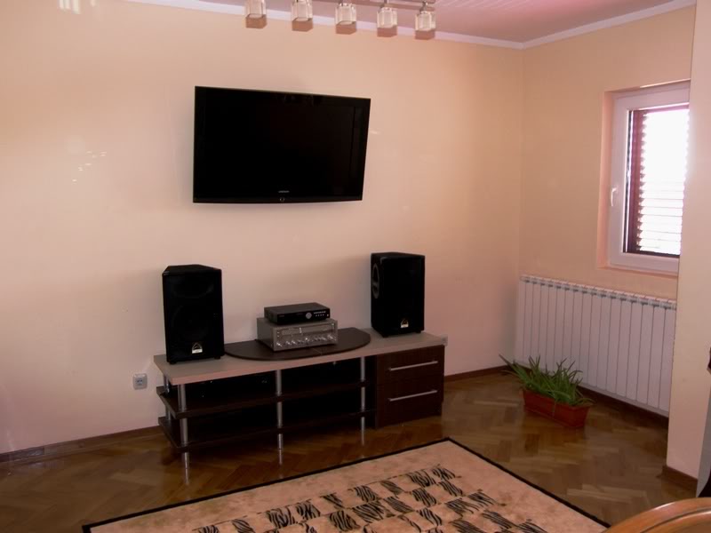 Budva, Karadağ’daki evde oturma odası: TV ünitesi, ses sistemi, parke zemin ve kalorifer radyatörü.