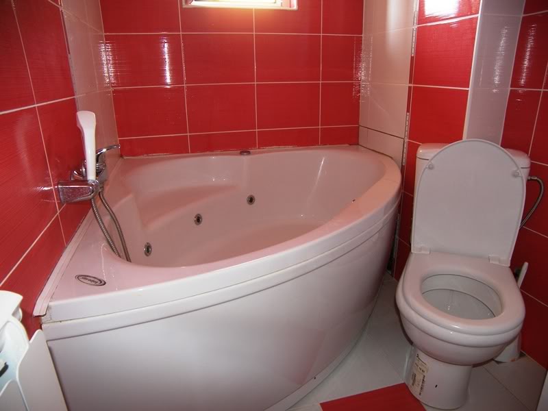 Satılık evde köşe hidromasajlı küvet ve kırmızı fayanslı banyo, Budva, Karadağ.