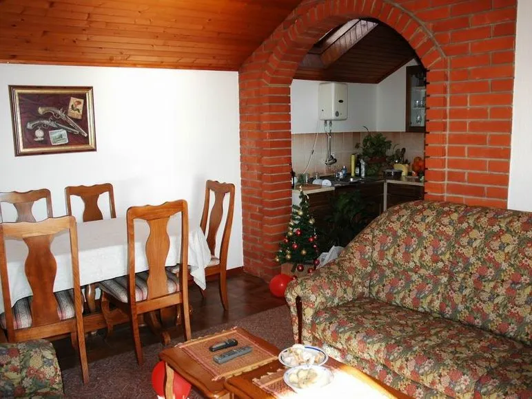Wohnzimmer mit Sofa, Couchtisch, Essbereich und Backsteinbogen zur Küche.