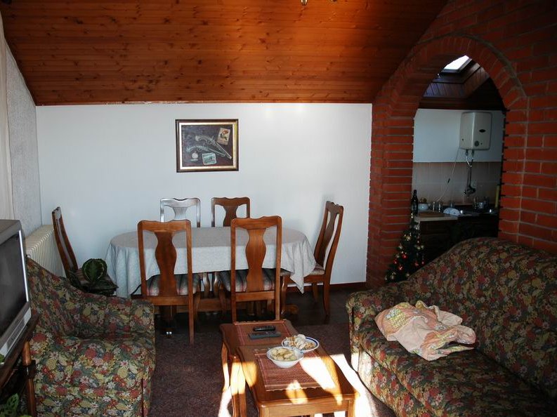 Wohnzimmer mit Essbereich in einem Haus in Herceg Novi, Montenegro: Holzdecke, Ziegelbogen und Polstermöbel.