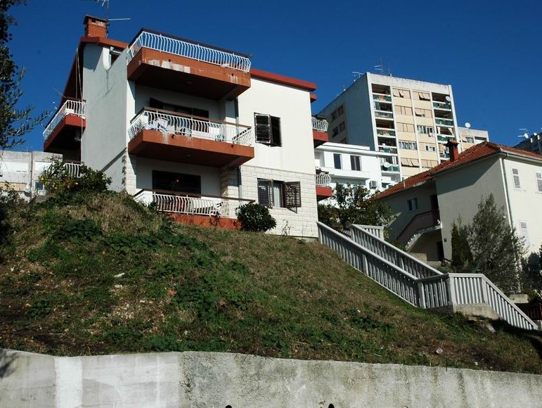 Dreistöckiges Wohnhaus mit Balkonen und Treppe auf einem Hügel in Herceg Novi, Montenegro.