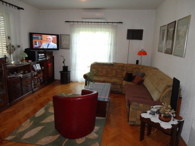Gemütliches Wohnzimmer in einem Haus in Herceg Novi, Montenegro: Ecksofa, Parkett, Klimaanlage und Zugang zur Terrasse.