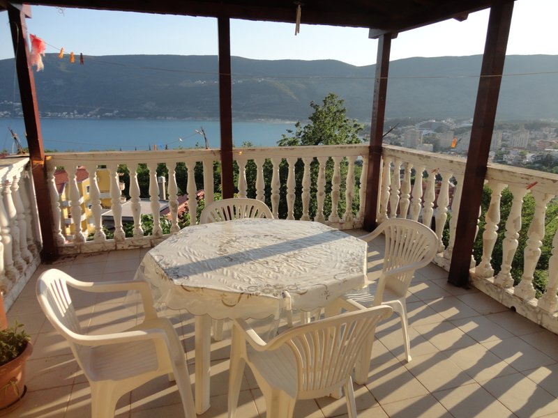 Terrasse mit Blick auf das Meer und die Berge in einem Haus, Herceg Novi, Montenegro: Kunststoffmöbel und Balustrade auf dem Balkon.