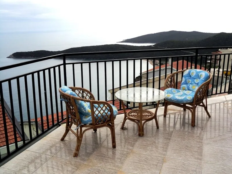 Balkon der Villa in Budva, Montenegro: Rattanmöbel, Glastisch und Panoramablick auf das Meer und die Berge.