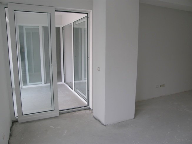 Salon avec baies vitrées panoramiques et accès au balcon dans un nouvel appartement, Pržno, Monténégro, finition brute.