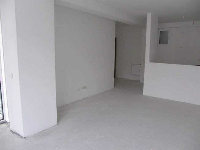 Salon dans un appartement brut à Pržno, Monténégro : murs clairs, sol en béton et agencement prêt pour rénovation.