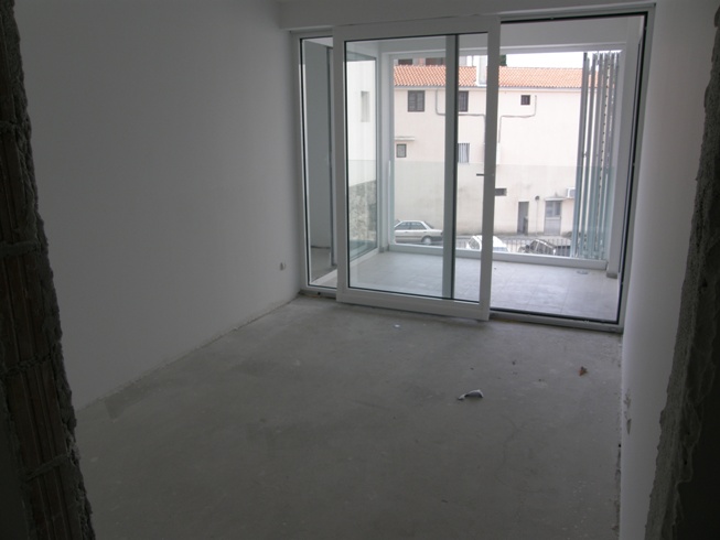 Salon dans un immeuble neuf à Pržno, Monténégro : baies panoramiques, accès à la terrasse, appartement en finition brute.