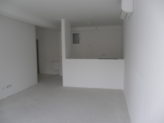 Salon dans un nouvel appartement brut à Pržno, Monténégro : murs blancs, coin cuisine et climatisation installée.