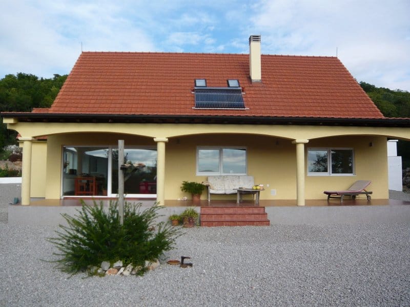 Privathaus in Nikšić, Montenegro: Fassade mit Terrasse, Säulen, Ziegeldach und Solarkollektoren.