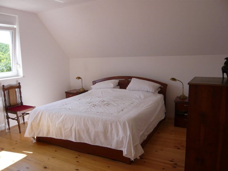 Gemütliches Schlafzimmer mit Doppelbett und Holzboden in einem Haus zum Verkauf in Nikšić, Montenegro.