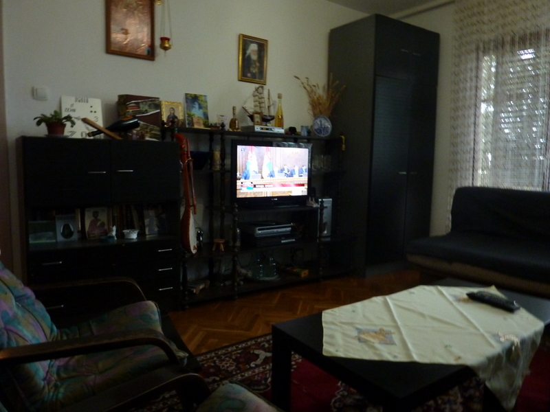 Wohnzimmer mit dunklen Möbeln, Fernseher und gemütlicher Sitzecke in einem zum Verkauf stehenden Haus in Sutomore, Montenegro.