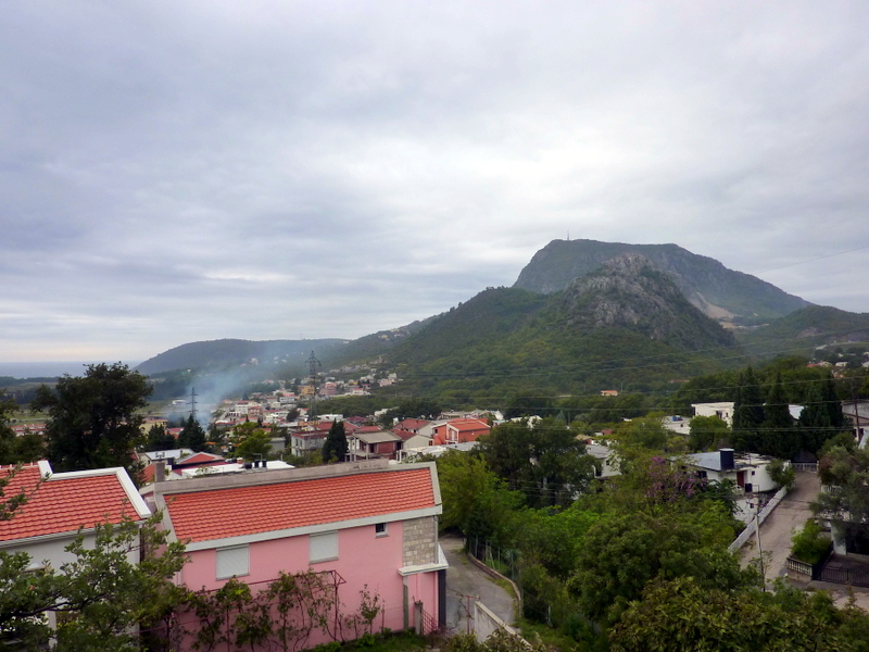 Panoramablick auf die Berge und die Stadt Sutomore in Montenegro, Privathäuser mit roten Ziegeldächern und grüne Landschaft.