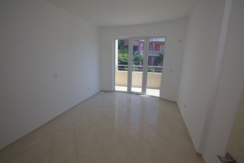 Helles, leeres Wohnzimmer mit Fliesenboden und Zugang zum Balkon in einem Haus, Stadt Uteha, Montenegro.