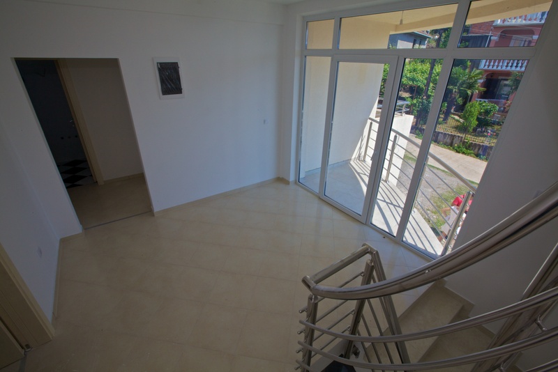 Helles Wohnzimmer mit Panoramafenstern und Zugang zum Balkon in einem Haus, Stadt Uteha, Montenegro. Blick auf die Treppe und den Garten.