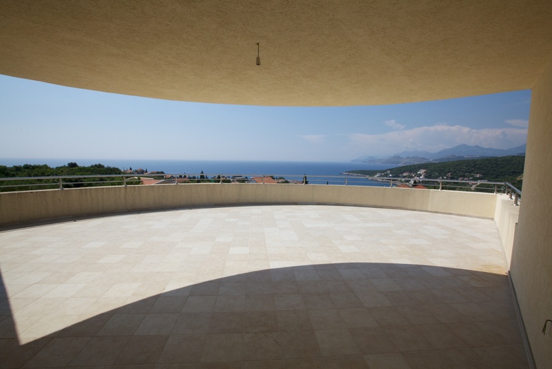 Geräumige Terrasse mit Panoramablick auf das Meer in einem Haus, Stadt Uteha, Montenegro. Helle Fliesen und ein Metallgeländer.