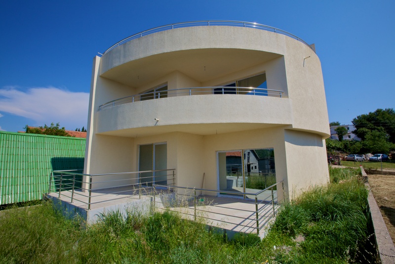 Modernes zweistöckiges Haus mit Terrassen und Panoramafenstern in Uteha, Montenegro. Rund geformte Fassade des Gebäudes.