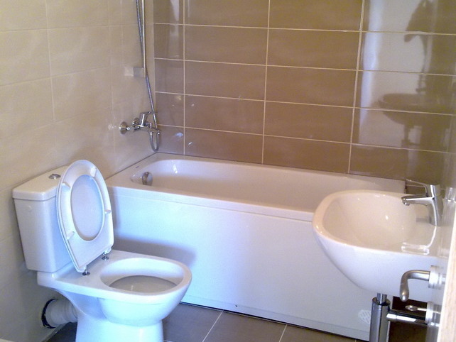 Modernes Badezimmer mit weißer Sanitärkeramik und beigen Fliesen in einer zum Verkauf stehenden Wohnung, Budva, Montenegro.