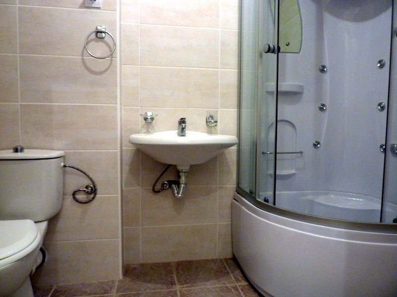 Badezimmer in einer Wohnung in Bečići, Montenegro: beige Fliesen, Duschkabine mit Hydromassage und Sanitäranlagen.