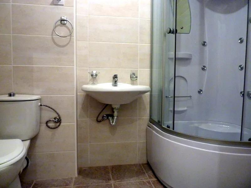 Badezimmer in einer Wohnung in Bečići, Montenegro: beige Fliesen, Duschkabine mit Hydromassage und Sanitäranlagen.