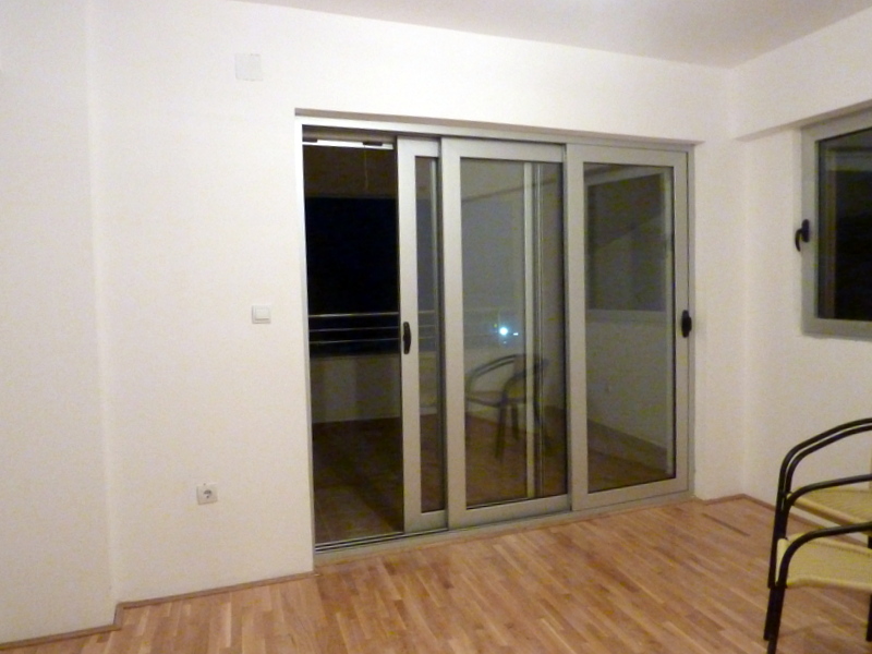 Wohnzimmer in einer Wohnung in Bečići, Montenegro: helle Ausstattung, Panoramabalkontüren und Zugang zum Balkon.