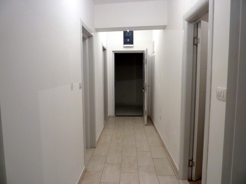 Heller Flur in einer Wohnung in Bečići, Montenegro: weiße Wände, Fliesenboden und Innentüren im modernen Stil.