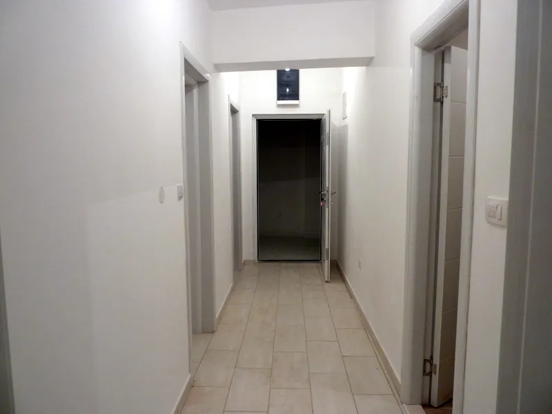 Heller Flur in einer Wohnung in Bečići, Montenegro: weiße Wände, Fliesenboden und Innentüren im modernen Stil.
