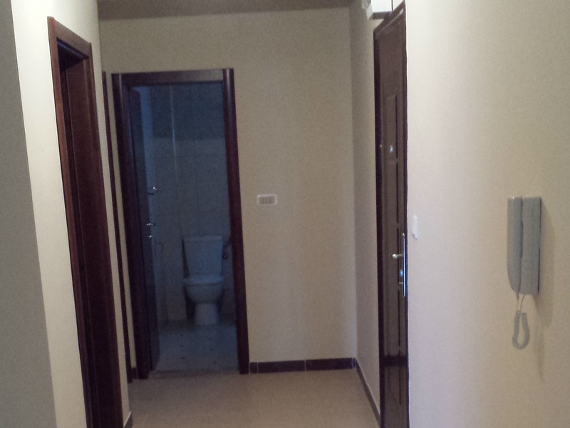 Flur mit Tür zum Badezimmer in einer Wohnung in Pržno, Montenegro: helle Wände, dunkle Innentüren und Gegensprechanlage.