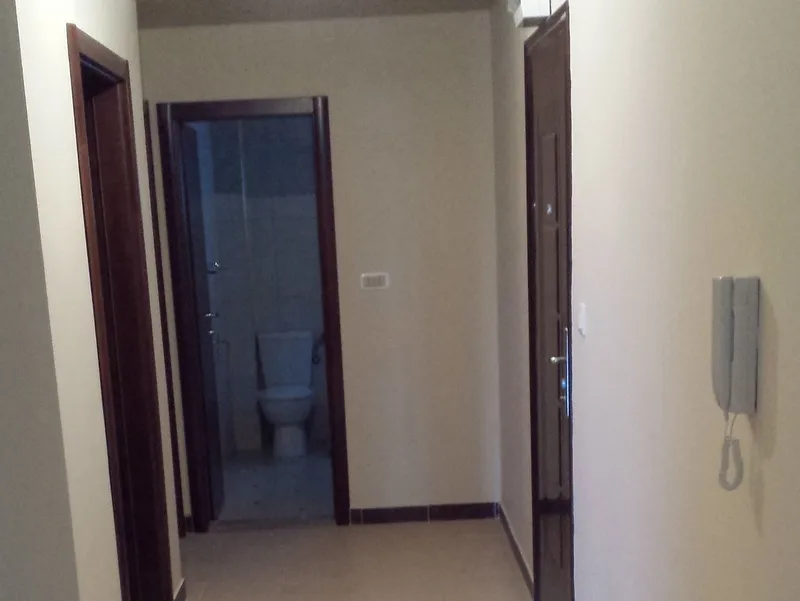 Flur mit Tür zum Badezimmer in einer Wohnung in Pržno, Montenegro: helle Wände, dunkle Innentüren und Gegensprechanlage.