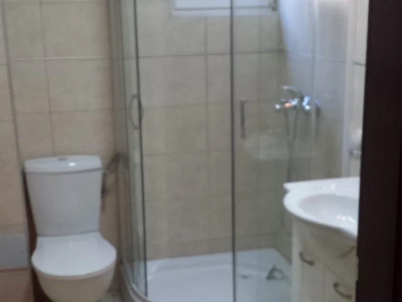 Badezimmer mit Duschkabine und hellen Fliesen in einer Wohnung zum Verkauf, Pržno, Montenegro.