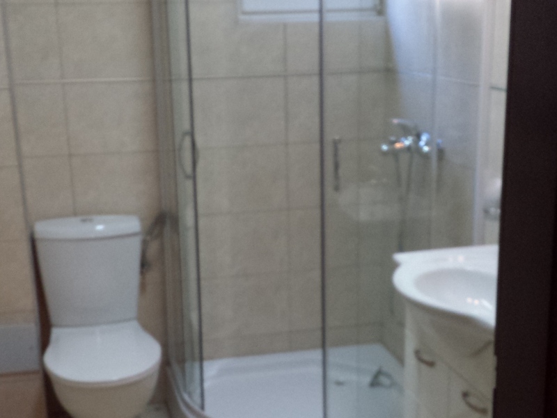 Badezimmer mit Duschkabine und hellen Fliesen in einer Wohnung zum Verkauf in Pržno, Montenegro.