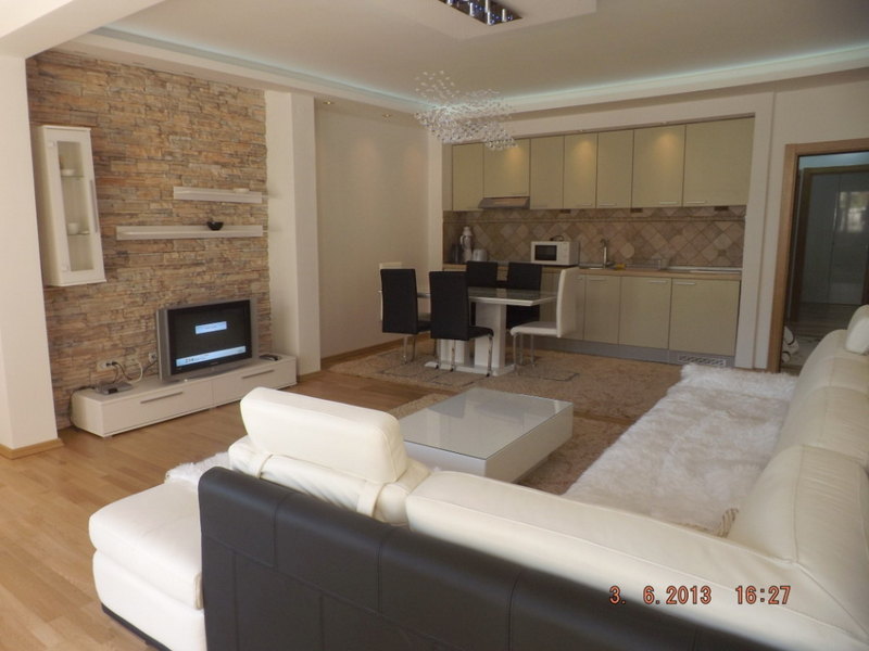 Wohnzimmer mit Küche in einer Wohnung in Pržno, Montenegro: helle Möbel, Steinverkleidung und modernes Interieur.