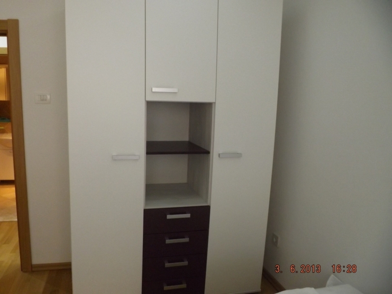 Moderner weißer Schrank mit dunklen Schubladen im Schlafzimmerinterieur einer Wohnung in Pržno, Montenegro.