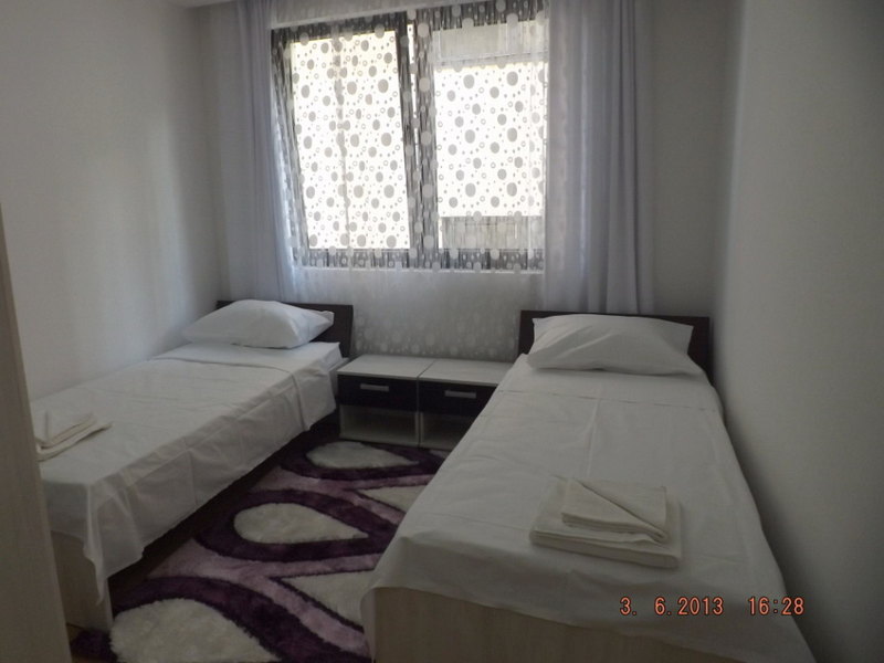 Helles Schlafzimmer mit zwei Einzelbetten in einer Wohnung in Pržno, Montenegro, mit Teppich und Nachttischen.