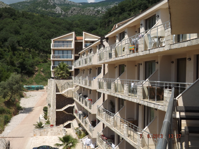 Moderner Wohnkomplex mit Terrassen in Pržno, Montenegro, vor Berglandschaft und Waldgebiet.