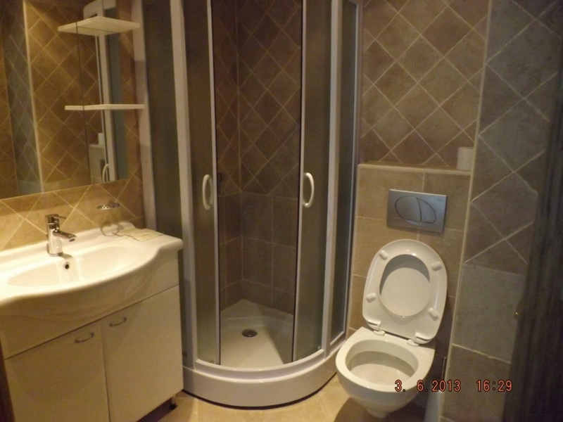 Badezimmer in einer Wohnung in Pržno, Montenegro: Duschkabine, weiße Waschtischkommode und wandhängendes WC.