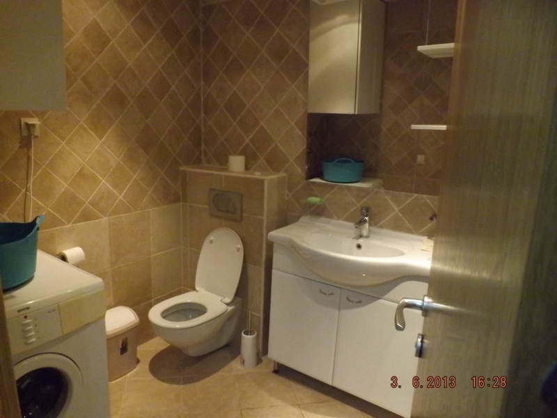 Badezimmer in einer Wohnung in Pržno, Montenegro: weiße Sanitärkeramik, Waschtischunterschrank und Fliesen in Beigetönen.