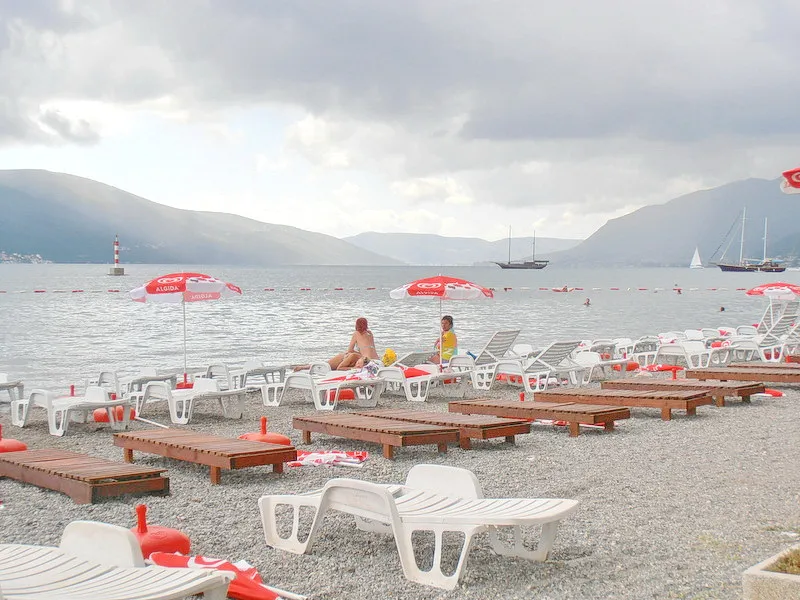Strand mit Sonnenliegen, Sonnenschirmen und dem Meer im Hintergrund