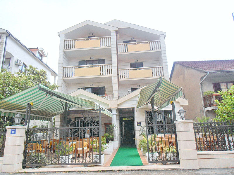 Trospratni hotel u Tivtu, Crna Gora, sa letnjom terasom, kovanom ogradom i balkonima na svakom spratu.