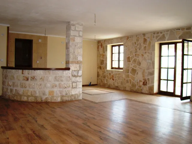 Ein leeres Interieur mit Holzboden, einer Steinsäule und einer geschwungenen Steintheke.