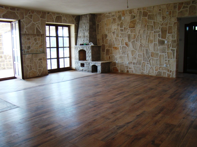 Karadağ, Petrovac’taki evde oturma odası: doğal taş duvar kaplamalı ve şömineli geniş bir oda.