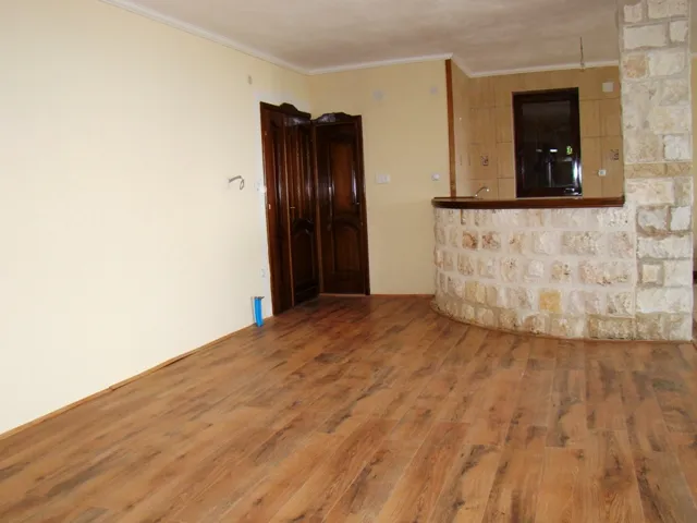 Ein Zimmer mit Holzboden, cremefarbenen Wänden, dunklen Holztüren und einer steingekleideten Bar.
