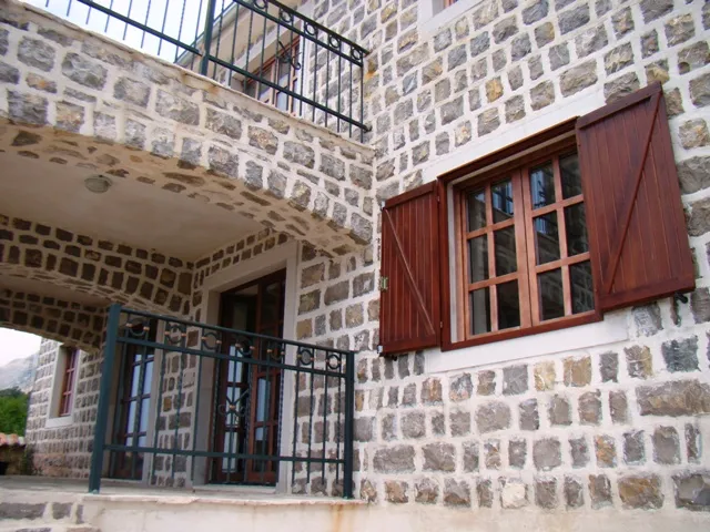 Steinfassade eines Hauses mit einem Holzfenster und Balkon