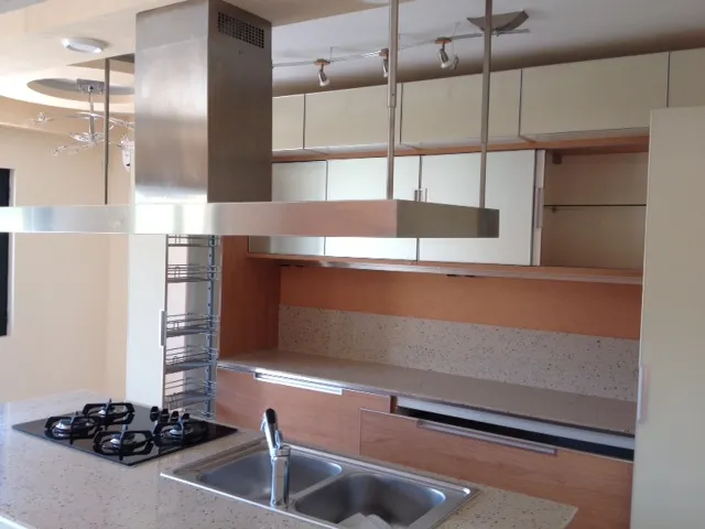 Moderne Küche in einer Wohnung in Budva, Montenegro: Kochinsel mit Gasherd, Spüle und Edelstahl-Dunstabzugshaube.