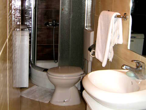 Kupatilo u kući u Herceg Novom, Crna Gora: tuš kabina, sanitarije, svetle pločice i veš mašina.