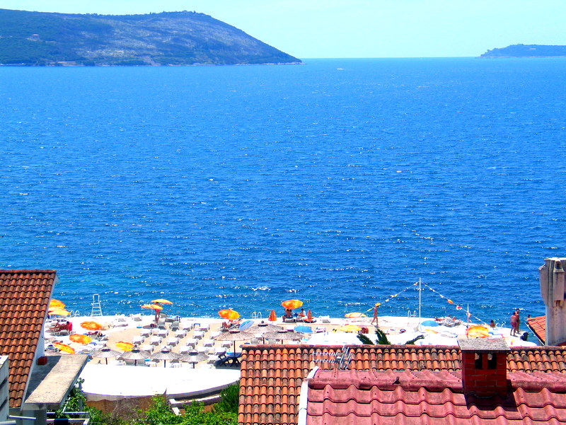 Panoramski pogled na more i plažu sa terase kuće u Herceg Novom, Crna Gora, sa krovovima od crepova u prvom planu.