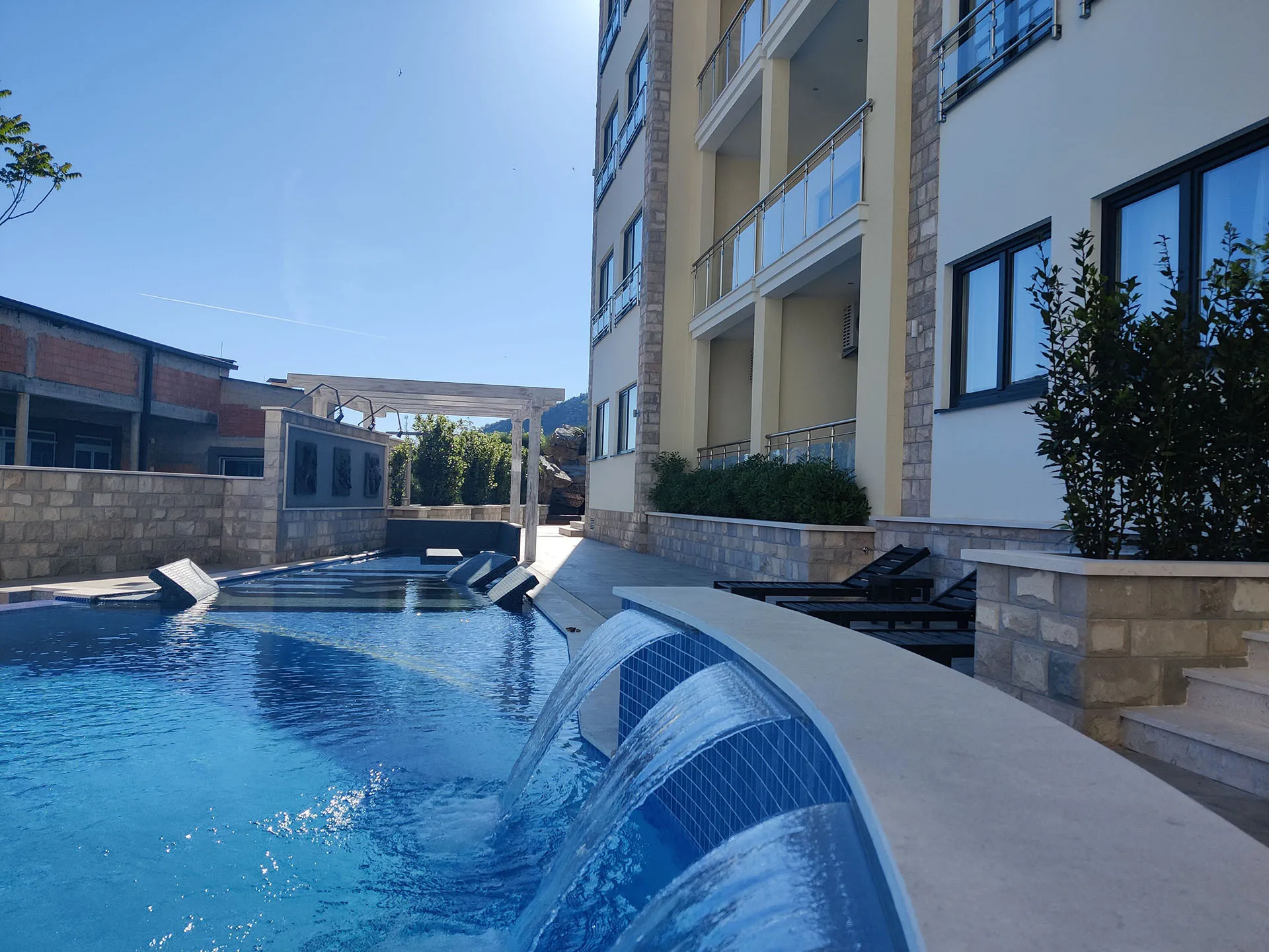Hotelpoolbereich mit Wasserspiel und Gebäude im Hintergrund