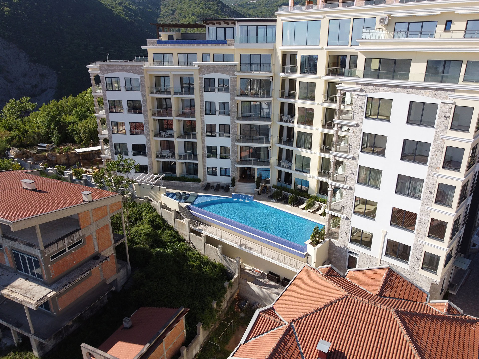Becici, Budva Rivierası, Karadağ’daki MonteDreams konut kompleksi: havuzlu ve dağ manzaralı modern bina.