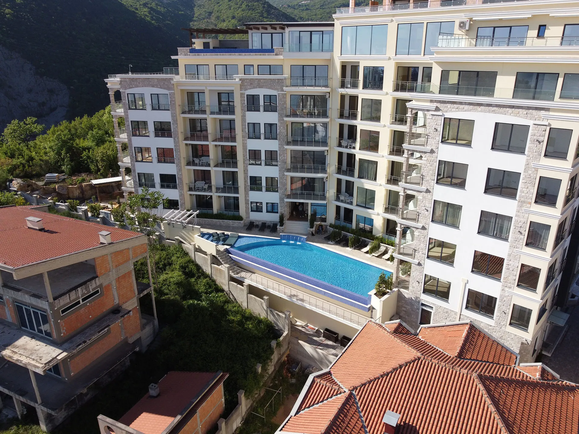 Luftaufnahme eines mehrstöckigen Hotels mit Swimmingpool und Bergen im Hintergrund